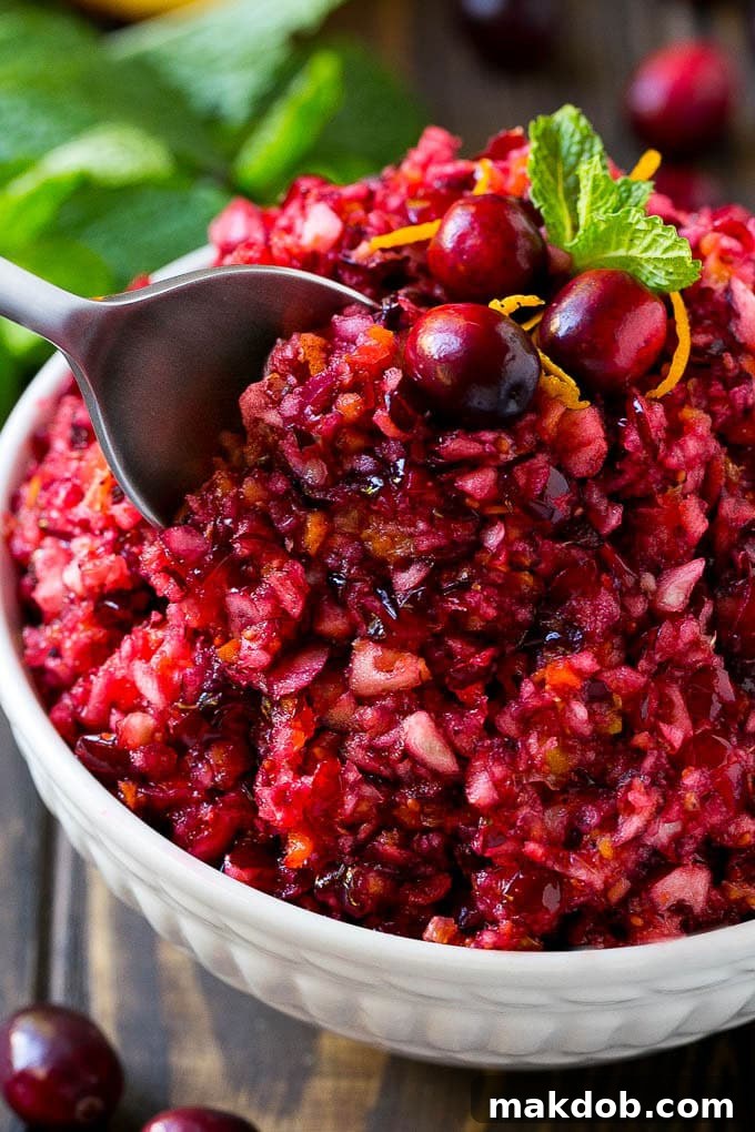 A serving spoon in a bowl of cranberry relish, showing its vibrant color and fresh texture.