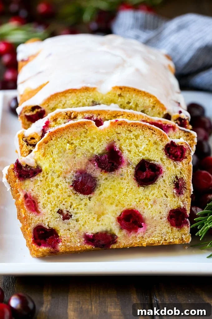 Sliced cranberry bread on a serving plate, showing its moist texture and vibrant cranberry pieces.