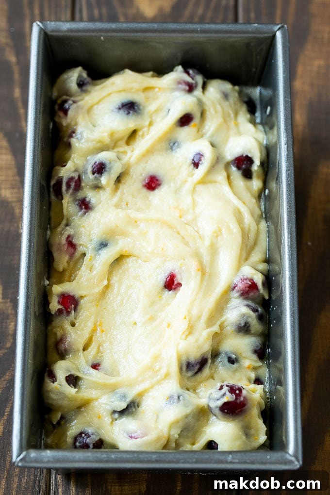 Cranberry bread batter smoothly spread into a loaf pan, ready for baking.