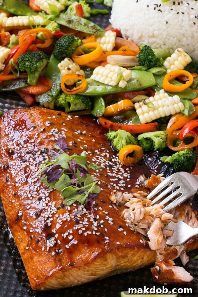 Asian salmon on a sheet pan with colorful vegetables, ready to be served with a side of rice.