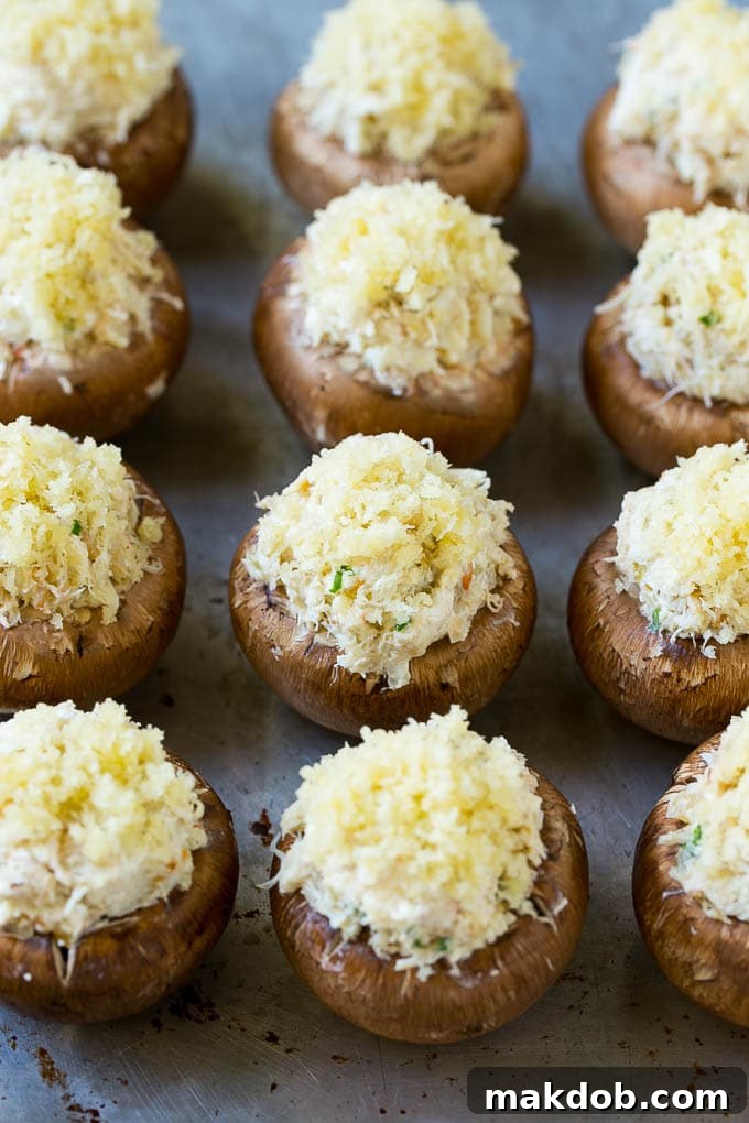 Uncooked crab stuffed mushrooms, beautifully arranged on a sheet pan, ready to bake.