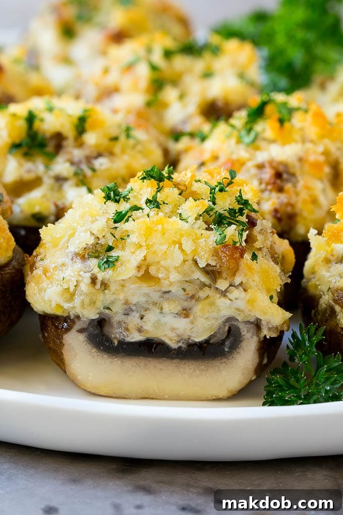 A cross-section of a beautifully baked sausage stuffed mushroom on a rustic serving platter, showcasing its rich, cheesy interior.