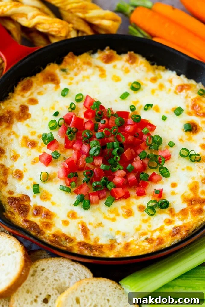 Crab Dip Recipe | Hot Crab Dip | Seafood Dip | Easy Appetizer | Dinner at the Zoo | Cheesy Dip Hot crab dip in a rustic skillet, generously garnished with fresh diced tomatoes and vibrant green onions, ready for serving with crusty bread.