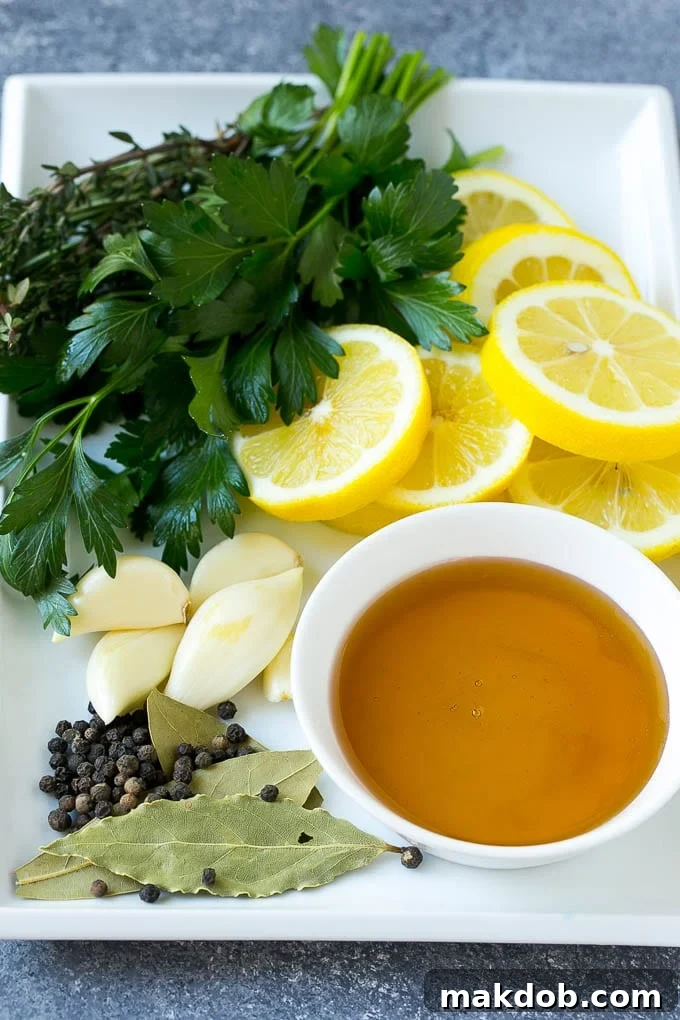 This chicken brine recipe is made with lemons, honey, fresh herbs and spices, and produces a juicy tender chicken every time! A foolproof way for succulent and flavorful roasted, smoked or fried chicken. A beautiful arrangement of chicken brine ingredients on a wooden surface, featuring a jar of golden honey, bright yellow lemons, cloves of garlic, whole peppercorns, and fresh sprigs of rosemary, thyme, and parsley.