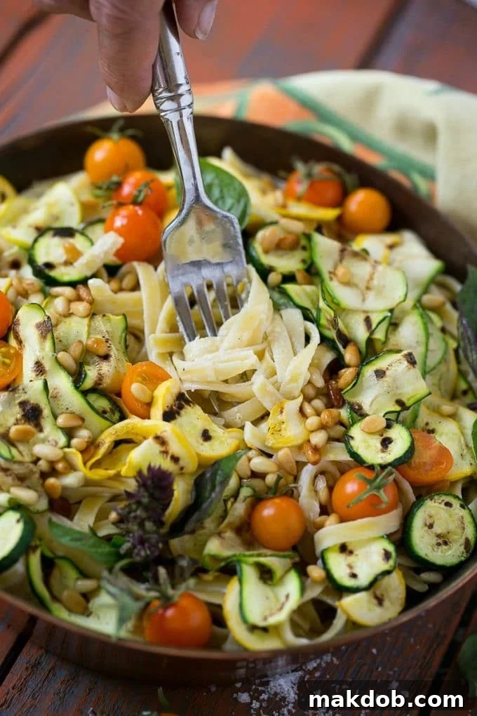 Zucchini Fettuccine Alfredo Recipe | Healthy Zucchini Fettuccine Alfredo | Lighter Zucchini Fettuccine Alfredo | Best Zucchini Fettuccine Alfredo A fork taking a bite of Zucchini Fettuccine Alfredo, showcasing the creamy pasta and vegetables.