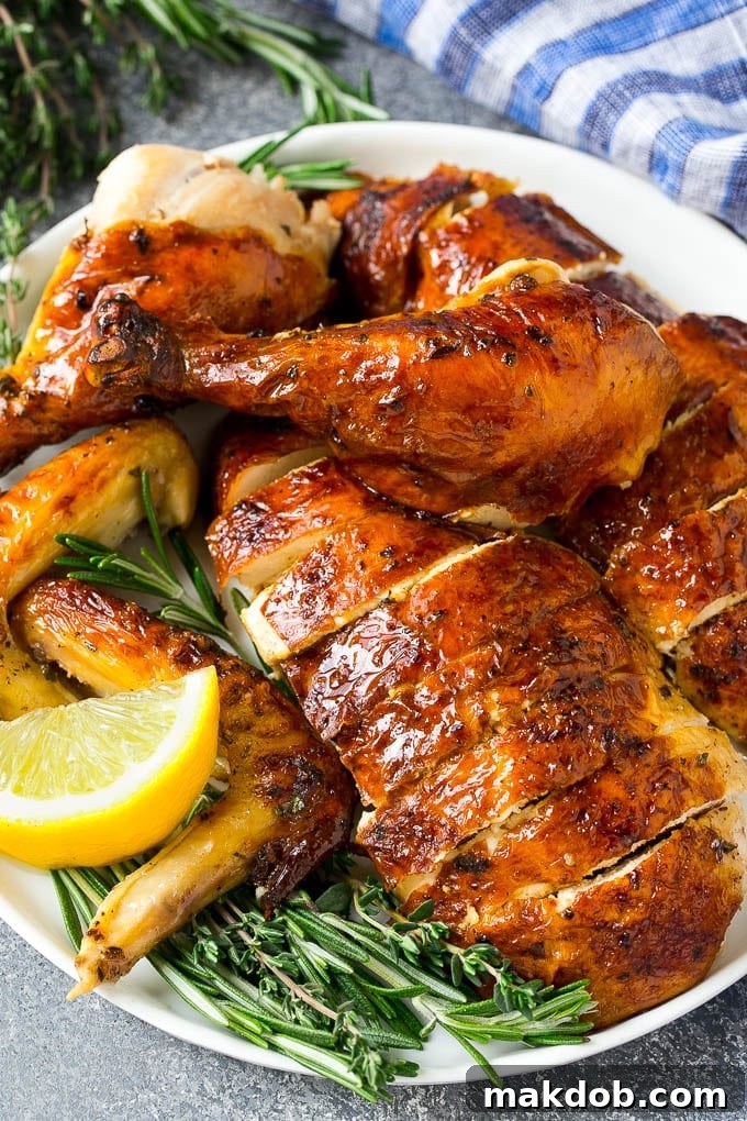 Carved roasted chicken on a serving platter with fresh herbs.