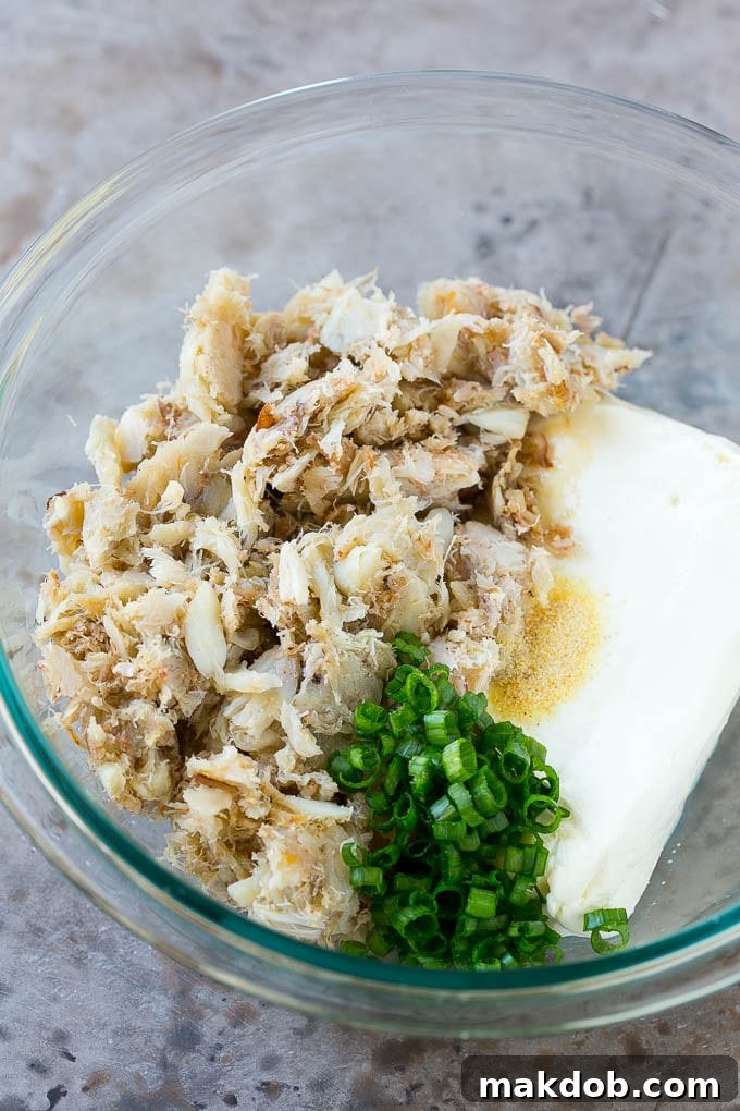 Crab Rangoon Recipe | Crab Wontons | Cream Cheese Wontons #crab #cheese #appetizer #snack #chinesefood #dinner #dinneratthezoo A mixing bowl filled with fresh crab meat, softened cream cheese, garlic powder, green onions, and Worcestershire sauce, ready to be combined.