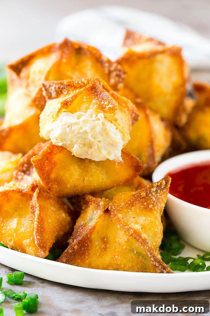Crab Rangoon Recipe | Crab Wontons | Cream Cheese Wontons #crab #cheese #appetizer #snack #chinesefood #dinner #dinneratthezoo A cross-section view of a crab rangoon, revealing its perfectly crispy exterior and a creamy, crab-filled center.