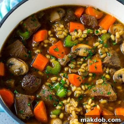 A pot full of beef barley soup made with beef stew meat, barley and vegetables all simmered together.