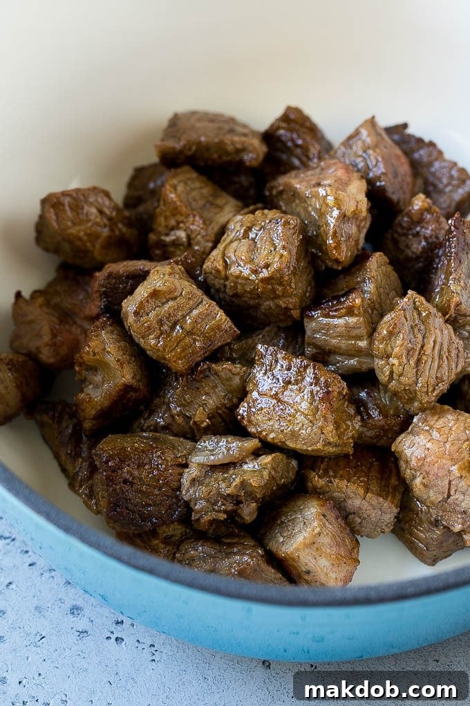 Seared beef stew meat browning in a large pot, creating a flavorful base for the soup.