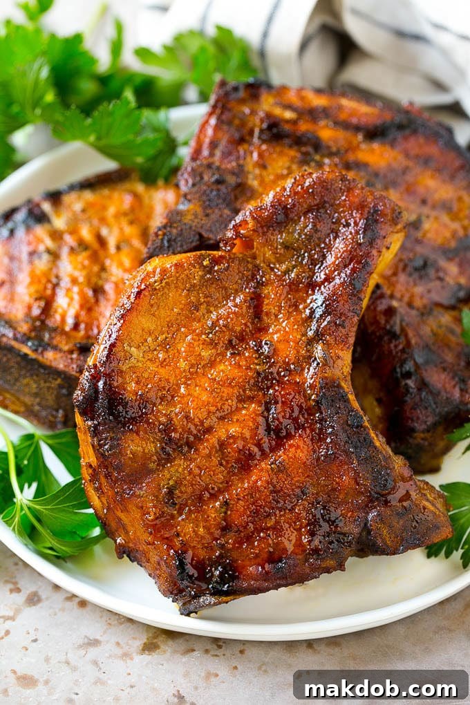Perfectly Smoked Pork Chops | Dinner Ideas with Pork #smokedpork #dinnerrecipe A plate of smoked pork chops garnished with fresh parsley, served with mashed potatoes and green beans.