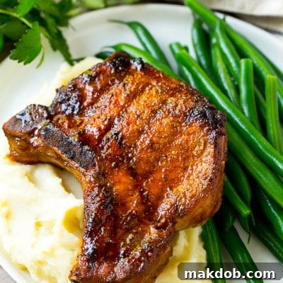 Smoky Pork Chop Perfection 2 Smoked pork chops over mashed potatoes with green beans on the side.