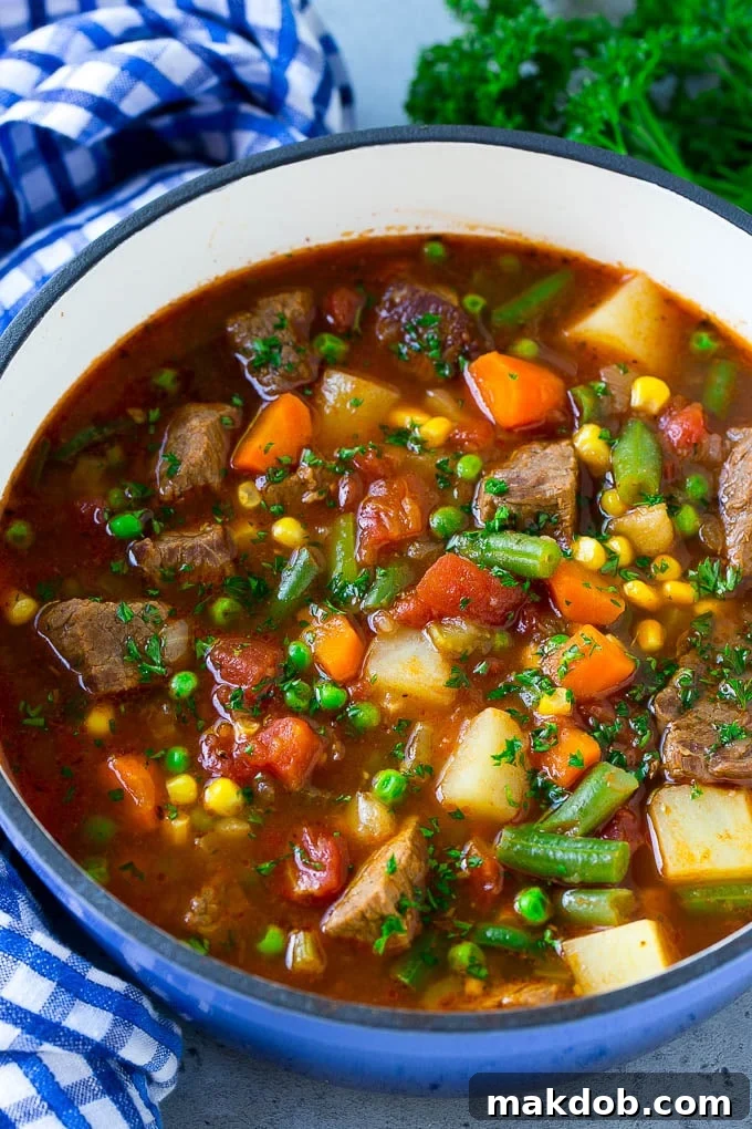 Delicious and hearty vegetable beef soup, packed with tender beef chunks, vibrant carrots, potatoes, green beans, corn, and peas, ready to be served.