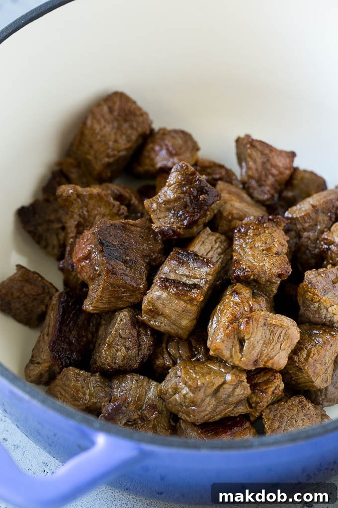 Close-up of browned pieces of beef stew meat sizzling in a large soup pot, ready for the next step of the recipe.