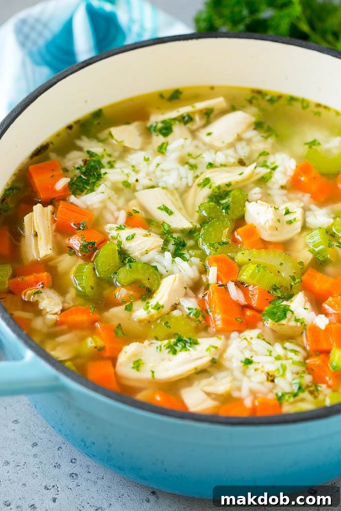 A vibrant blue pot overflowing with hot chicken and rice soup, garnished with freshly chopped parsley, ready to be served.