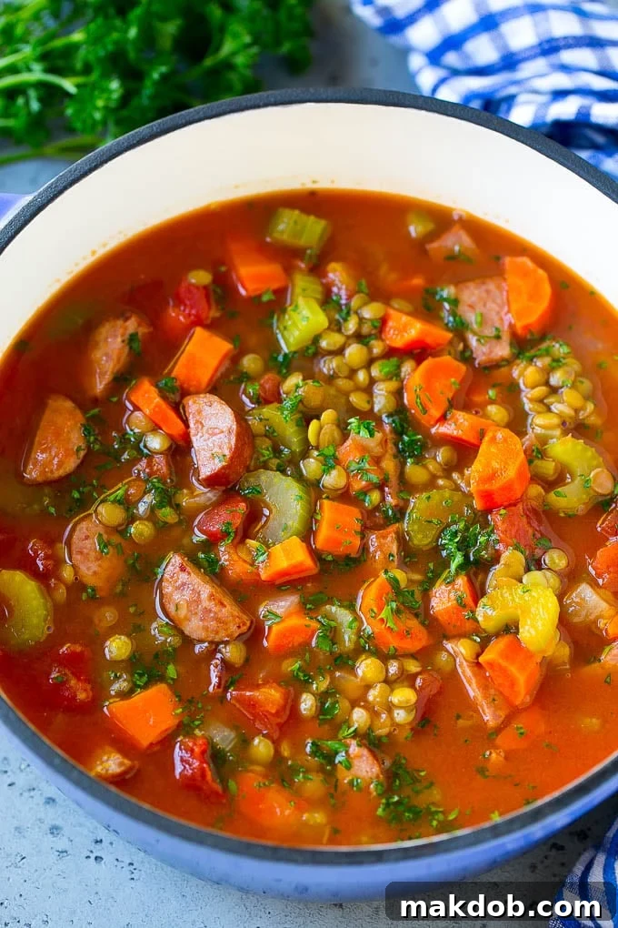 Lentil Soup Recipe | Sausage Lentil Soup #soup #lentils #sausage #dinner #glutenfree #dinneratthezoo A pot of lentil soup flavored with vegetables, tomatoes and smoked sausage, then garnished with chopped parsley.