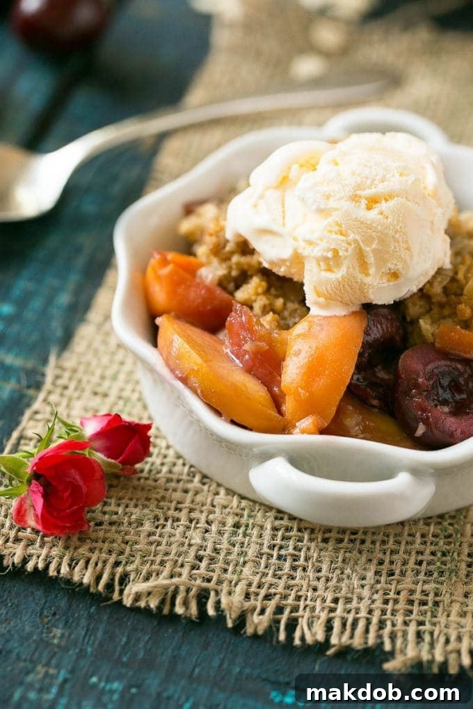 A close-up of a bowl of warm fruit crisp generously topped with a scoop of melting vanilla ice cream, creating a delightful contrast of temperatures and textures.