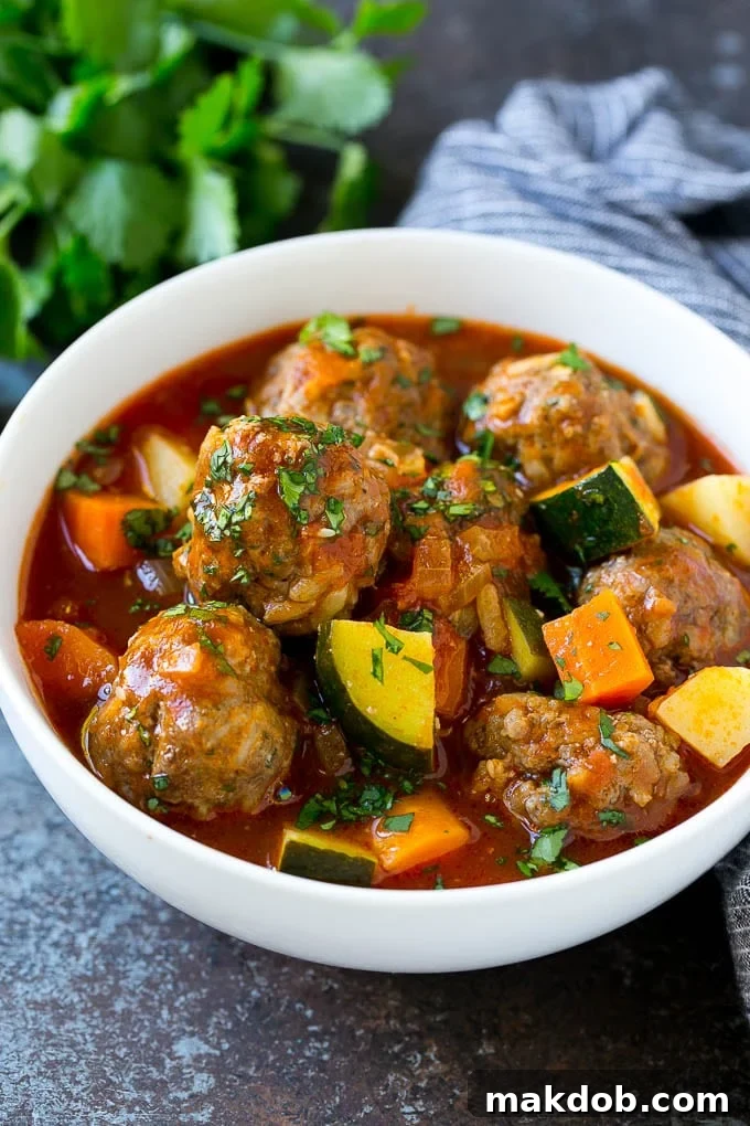 Albondigas Soup | Meatball Soup | Mexican Soup #soup #meatballs #beef #rice #glutenfree #dinner #dinneratthezoo #comfortfood A bowl of albondigas soup with meatballs, carrots, zucchini and tomatoes.