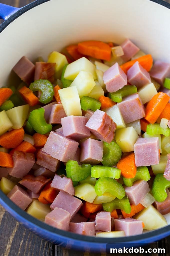 Soup Pot Simmering with Ham and Vegetables A close-up view of a pot filled with diced ham, carrots, Russet potatoes, and celery, gently simmering in a savory broth.