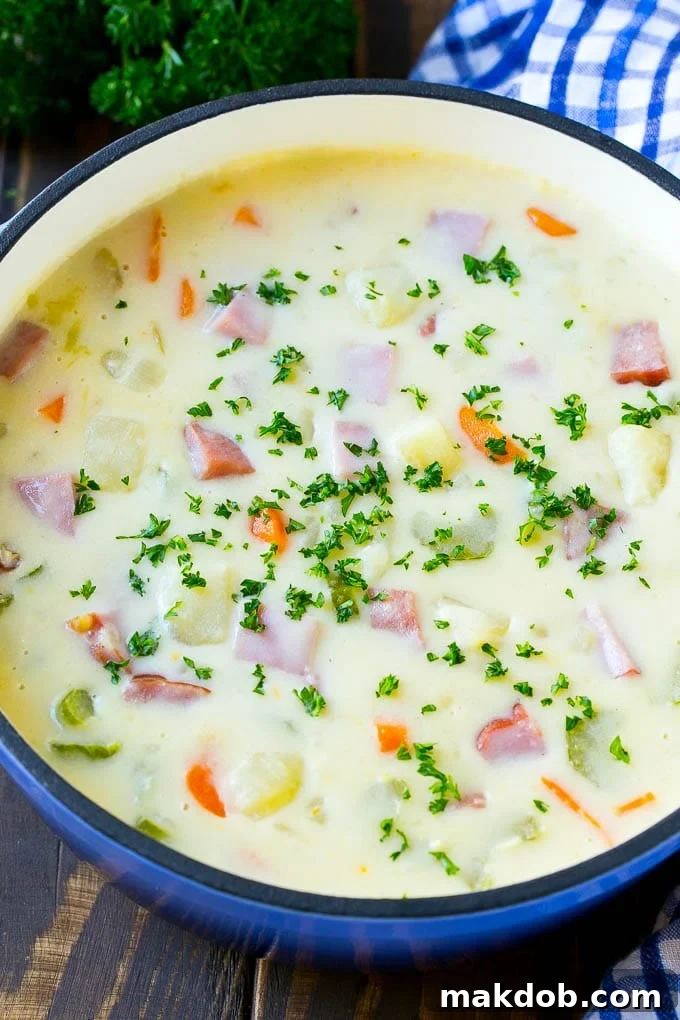 Delicious Ham and Potato Soup with Parsley A large pot of creamy ham and potato soup, generously garnished with fresh parsley, ready to be served.