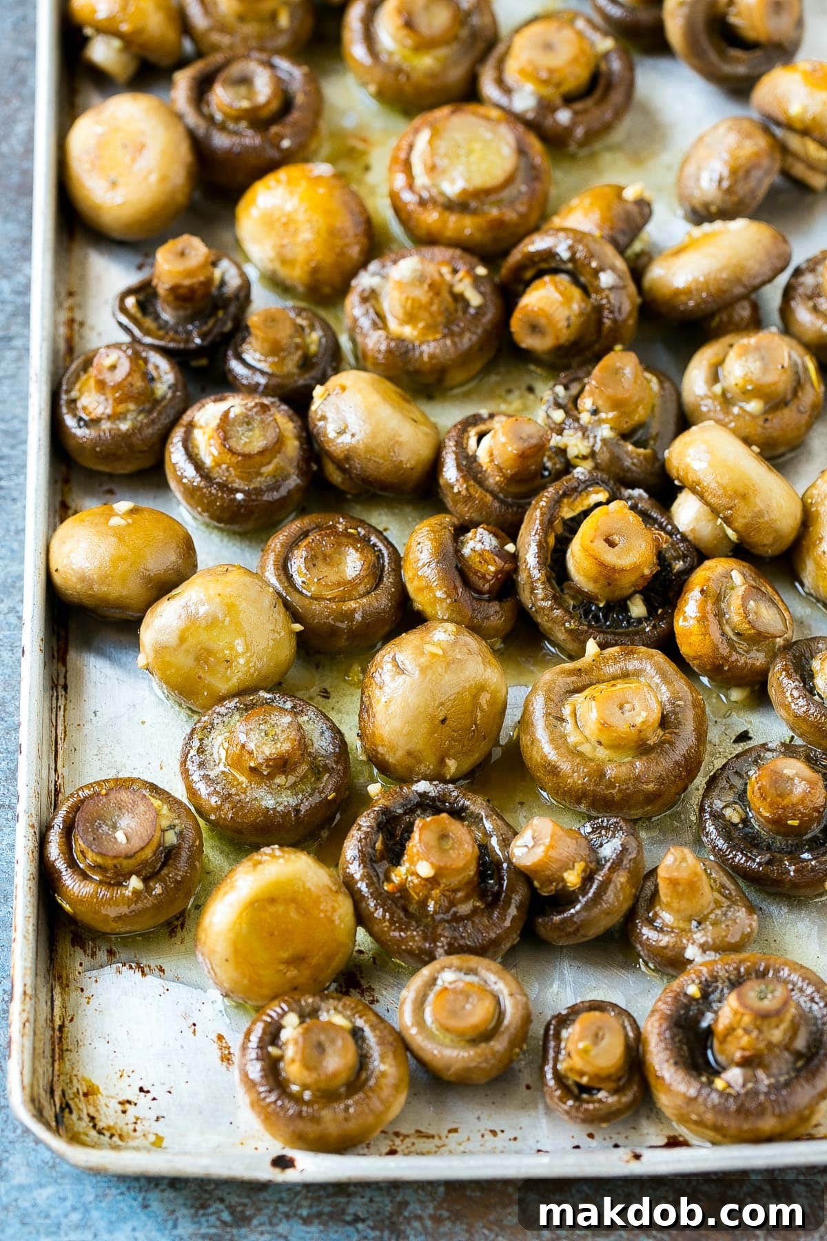Rich Garlic Butter Roasted Mushrooms 5 Cooked mushrooms on a sheet pan, glistening with garlic butter and fresh herbs.