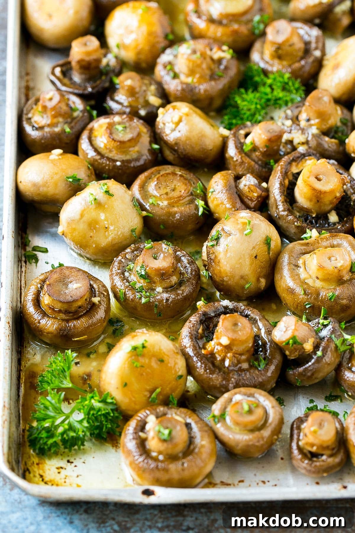 Rich Garlic Butter Roasted Mushrooms 6 Roasted mushrooms served on a pan, garnished with a sprinkle of fresh parsley.