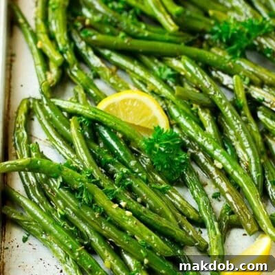 A pan of roasted green beans garnished with parsley and lemon.