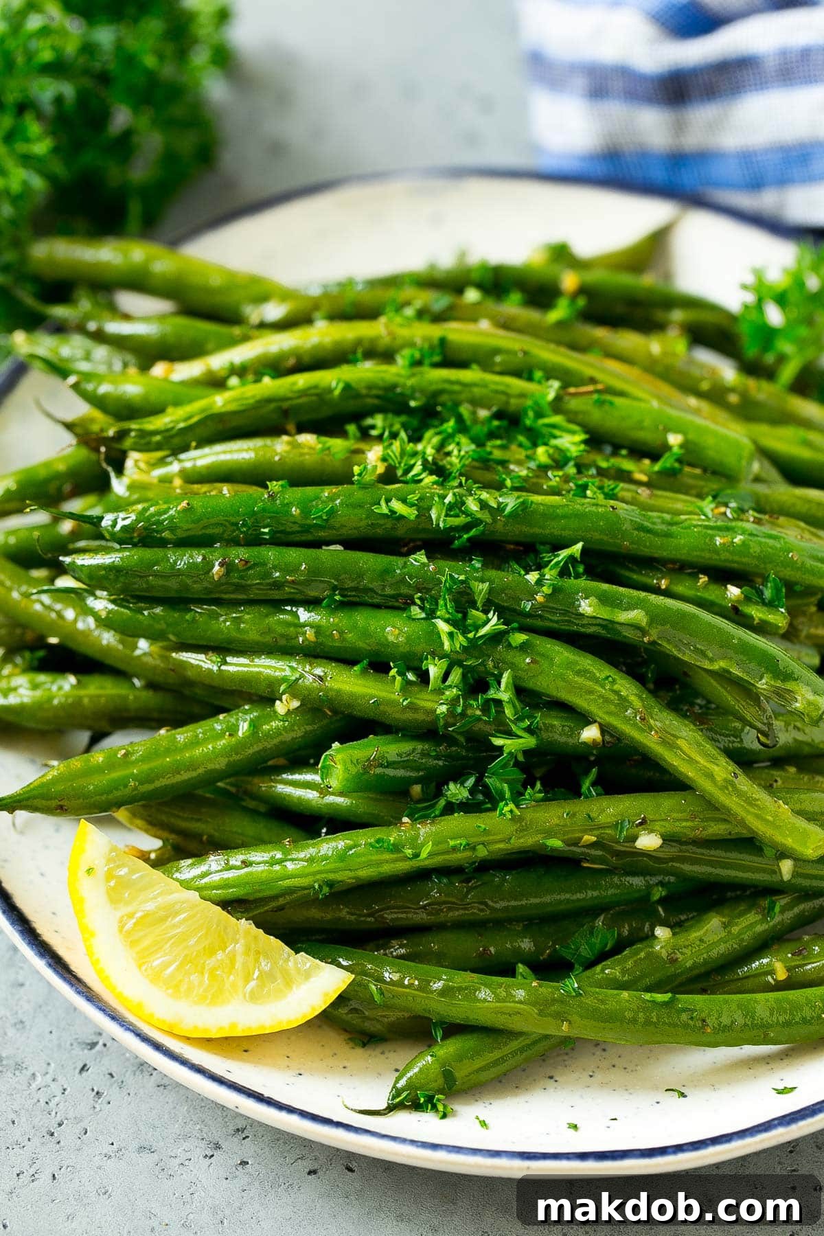 A serving plate of roasted green beans with a sprinkle of fresh parsley, elegantly presented.