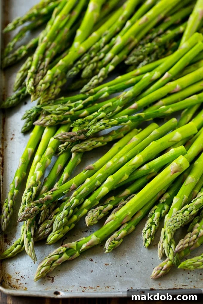 Raw asparagus spears on a sheet pan, ready for seasoning.