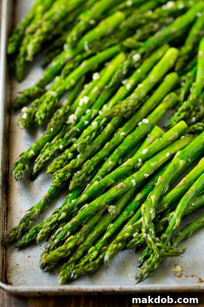 Roasted asparagus stalks with garlic and olive oil on a baking sheet, ready to be served.