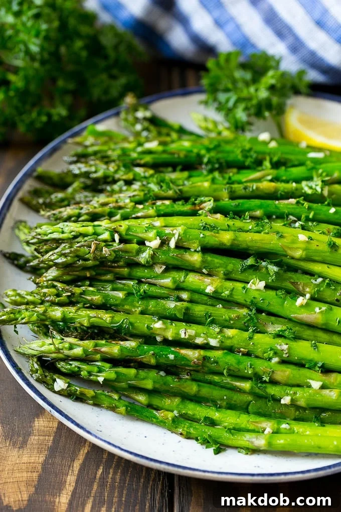 A serving plate of roasted asparagus topped with chopped parsley.