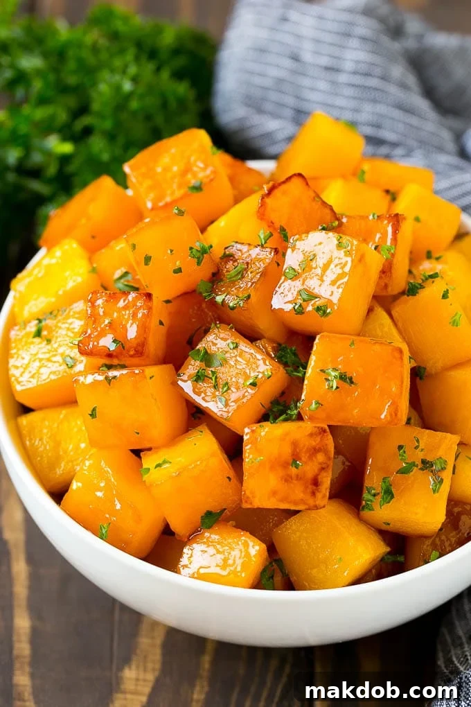 A bowl of roasted butternut squash made with brown sugar and maple syrup, then garnished with chopped parsley. A comforting and vibrant side dish for any meal.