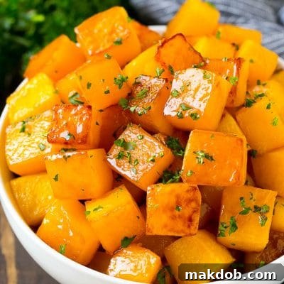 A bowl of roasted butternut squash made with brown sugar and maple syrup, then garnished with chopped parsley.