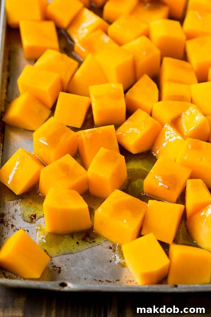 Cubes of winter squash coated in olive oil, brown sugar and maple syrup, ready to be roasted.