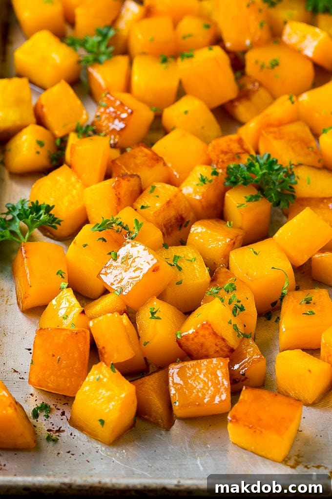 Roasted butternut squash with brown sugar and maple syrup, garnished with chopped parsley, served beautifully.