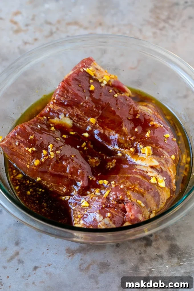 Raw flank steak in a bowl of marinade, ready for refrigeration.