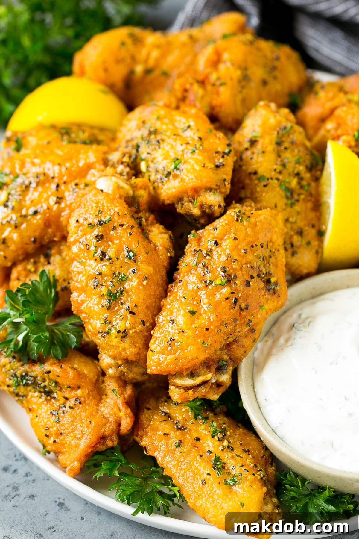 Citrus Peppered Wings 6 A beautifully arranged plate of golden-brown lemon pepper wings, served with a side of creamy ranch dipping sauce.