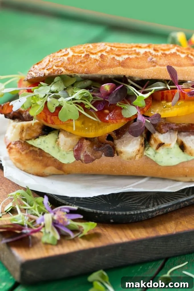 A beautifully layered chicken club sandwich showcasing grilled chicken, crispy bacon, ripe tomatoes, and fresh lettuce.