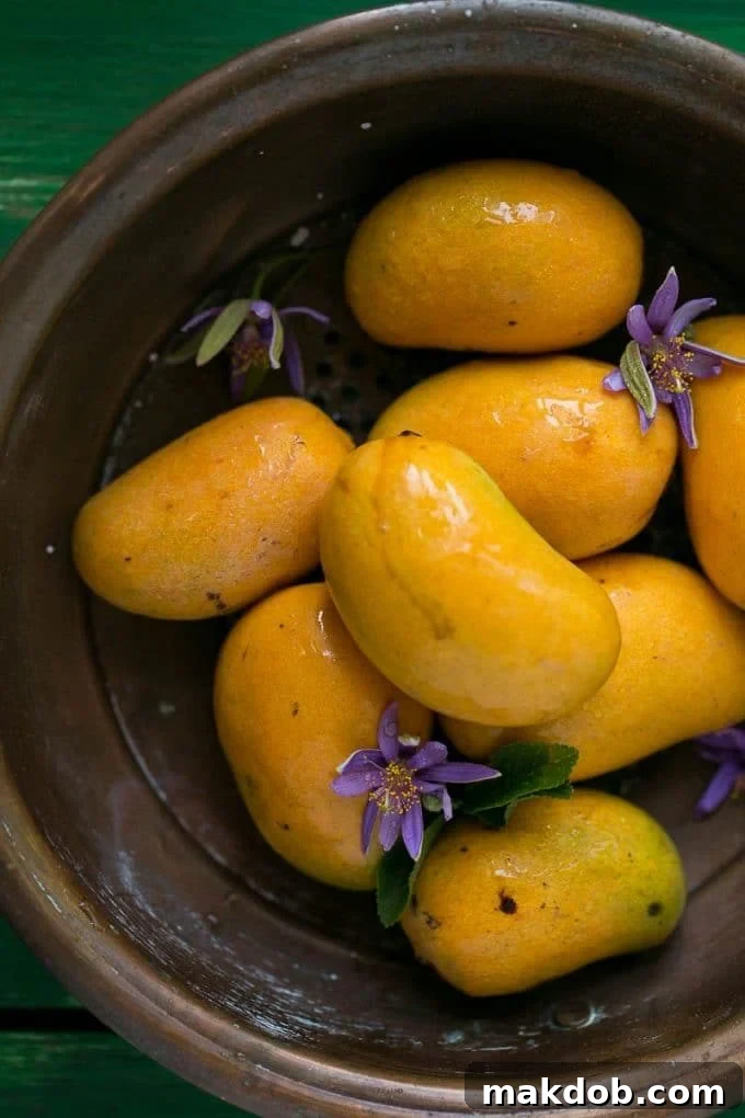 A close-up shot of fresh, ripe mangoes resting in a colander, ready for preparation.