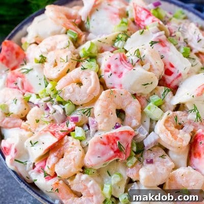 A serving bowl of seafood salad made with shrimp and imitation crab in a creamy dill dressing.