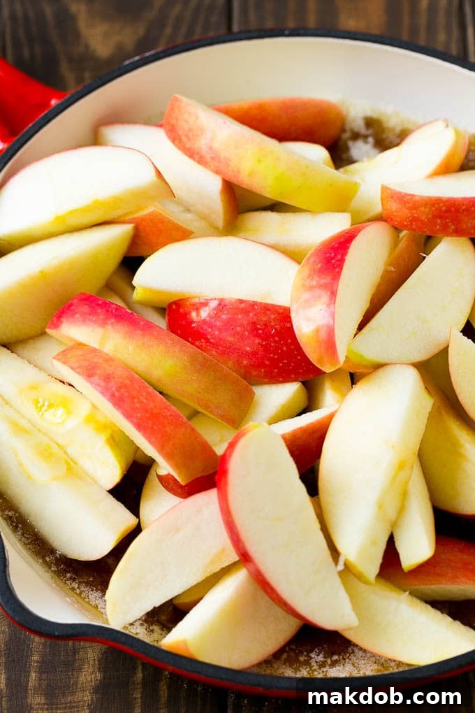 Sliced apples in a pan with butter, sugar and cinnamon.