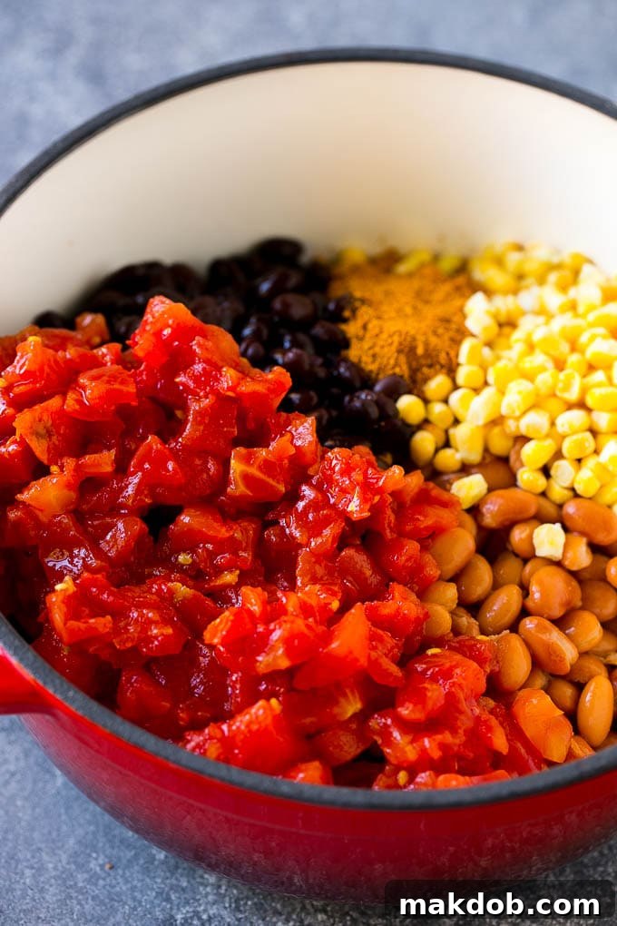 Ground beef, taco seasoning, canned tomatoes, beans and corn in a soup pot.