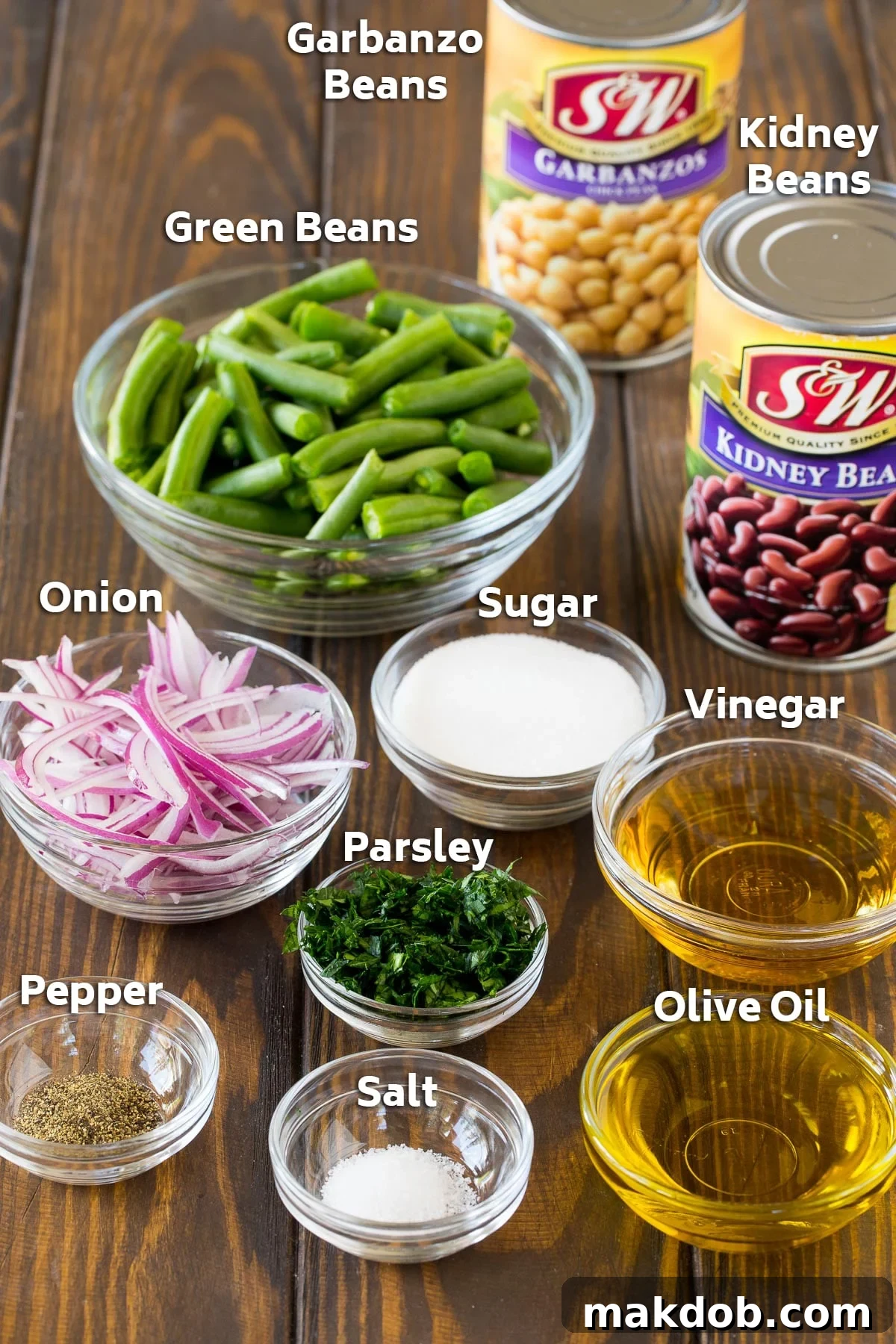 Ingredients for the three bean salad recipe, including fresh green beans, canned kidney and garbanzo beans, red onion, parsley, olive oil, vinegar, sugar, salt, and pepper.