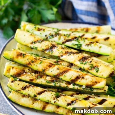 A plate of grilled zucchini garnished with lemon and herbs.
