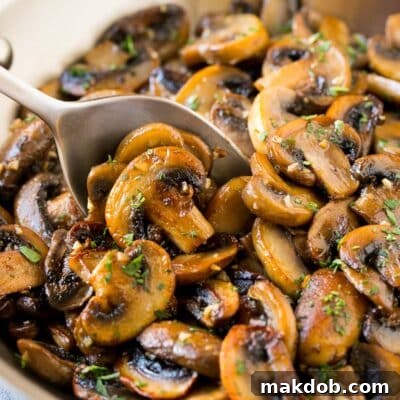 A pan of sauteed mushrooms with a serving spoon in it.
