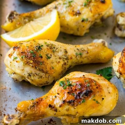 Baked chicken drumsticks flavored with garlic and herbs, then garnished with lemon wedges and parsley.