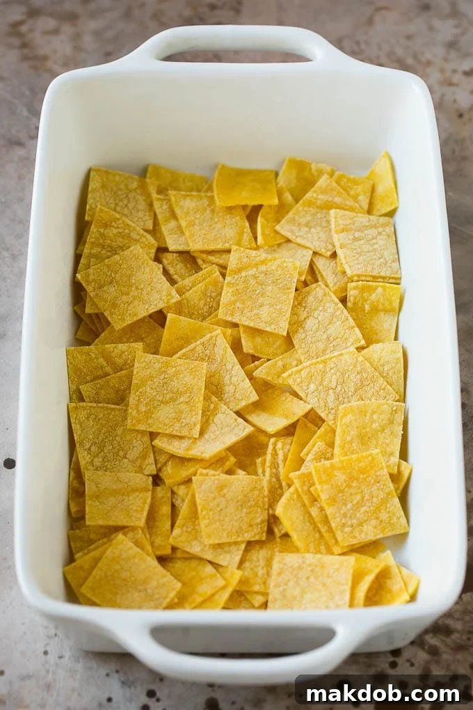Cut up corn tortillas layered neatly in the bottom of a casserole dish, ready for filling.