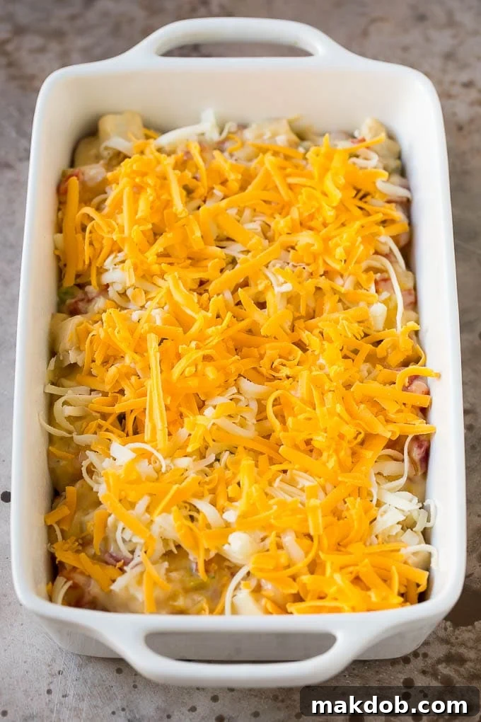 An unbaked King Ranch chicken casserole, perfectly layered with tortillas, chicken mixture, and cheese, ready for the oven.