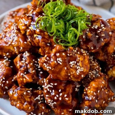 Korean fried chicken on a serving plate topped with curly green onions.