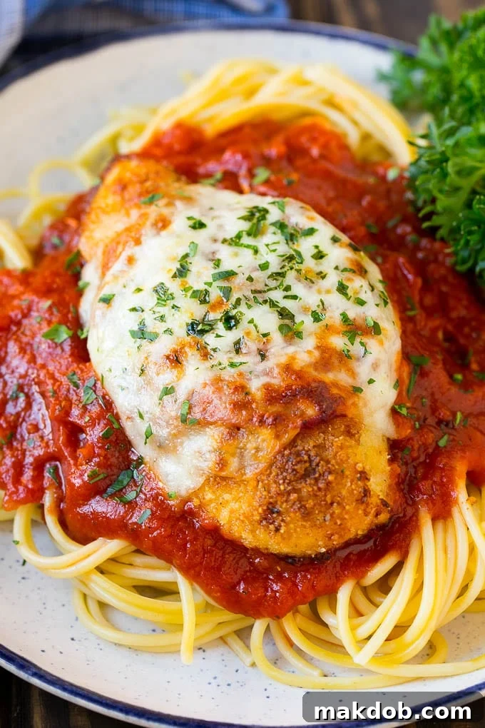 Baked chicken parmesan served over spaghetti with tomato sauce.